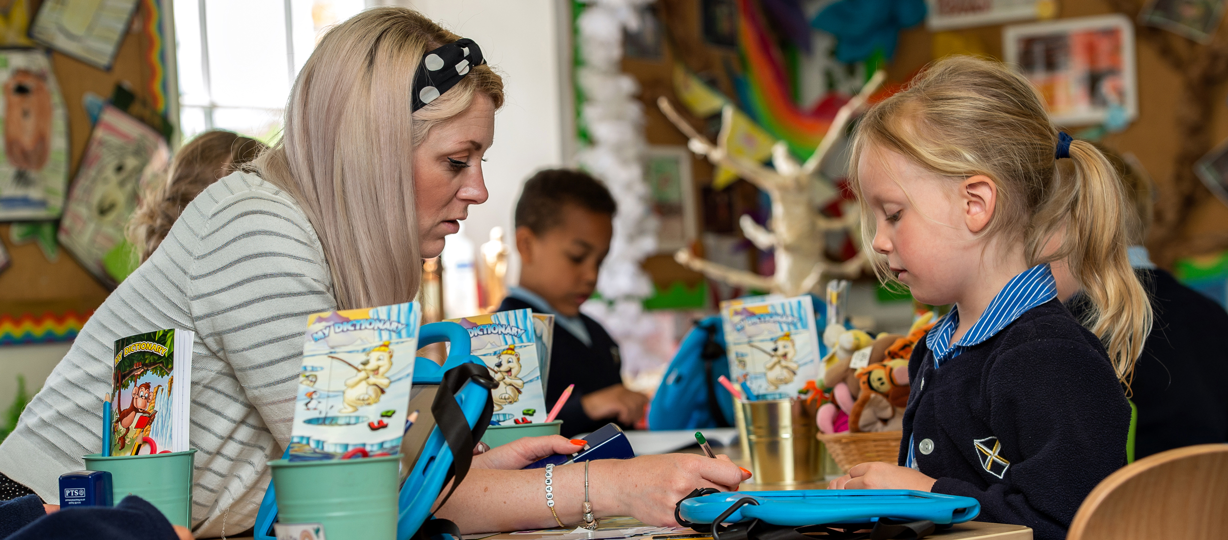teacher helping Wells Pre-Prep pupil in the classroom at our Independent School in Wells, Somerset