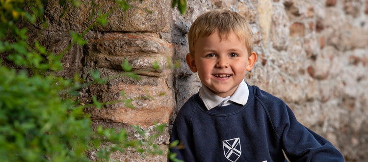 Young boy sitting by wall outside of our Independent Pre-Prep in Somerset